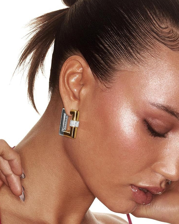 Close-up of a woman wearing a gold and blue earring with a blurred background